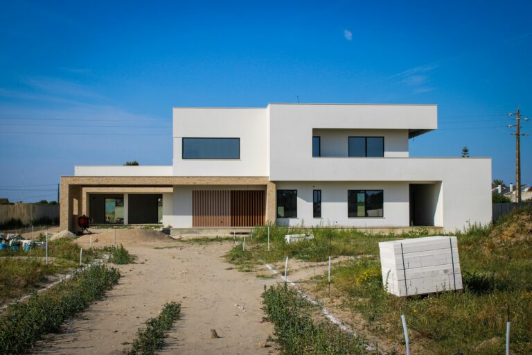 a large white house sitting on top of a dirt road